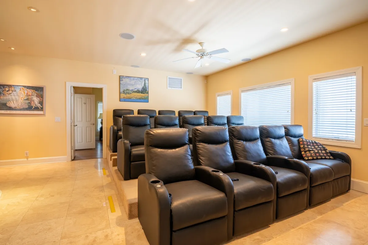 A plush home theater room with rows of reclining theater chairs, wall art, and softly filtered natural light from the windows. The setup is perfect for immersive movie nights with the whole group.
