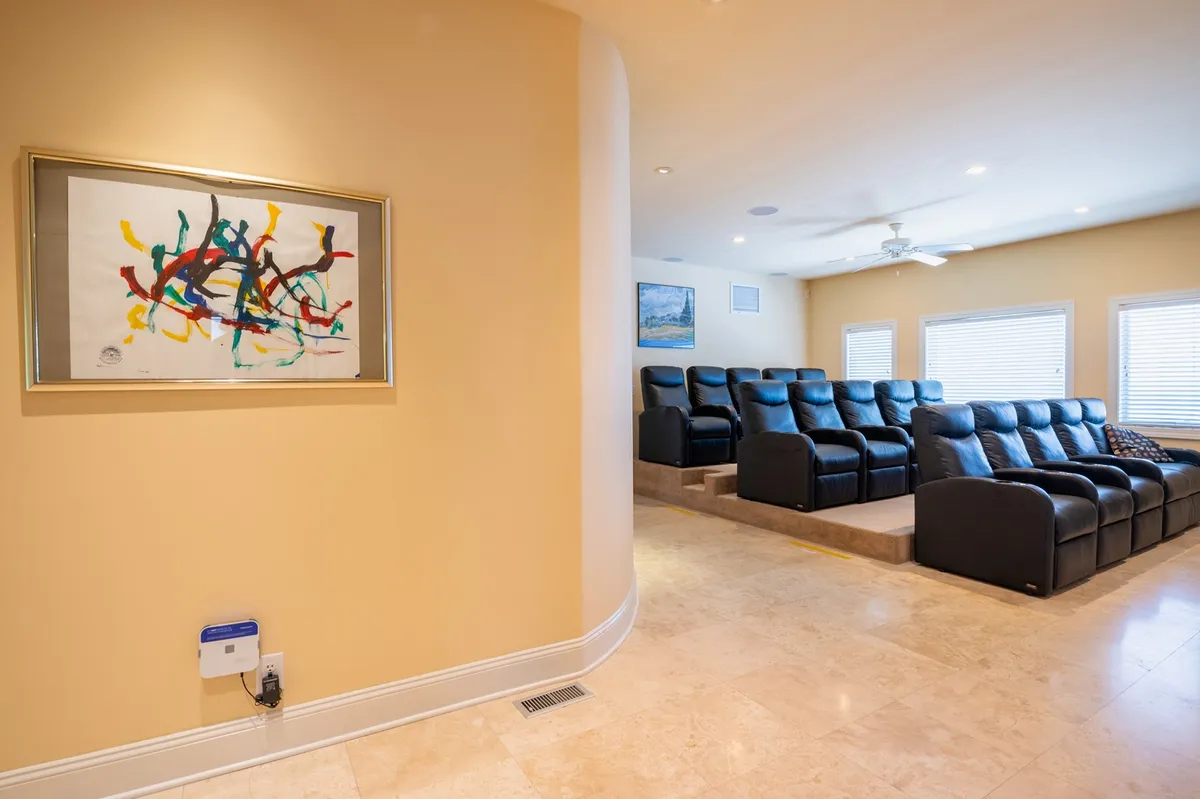 A cozy in-home theater room with plush, comfortable seating and framed abstract artwork on the wall. The lighting is soft and welcoming, creating a perfect atmosphere for movie nights and indoor entertainment.